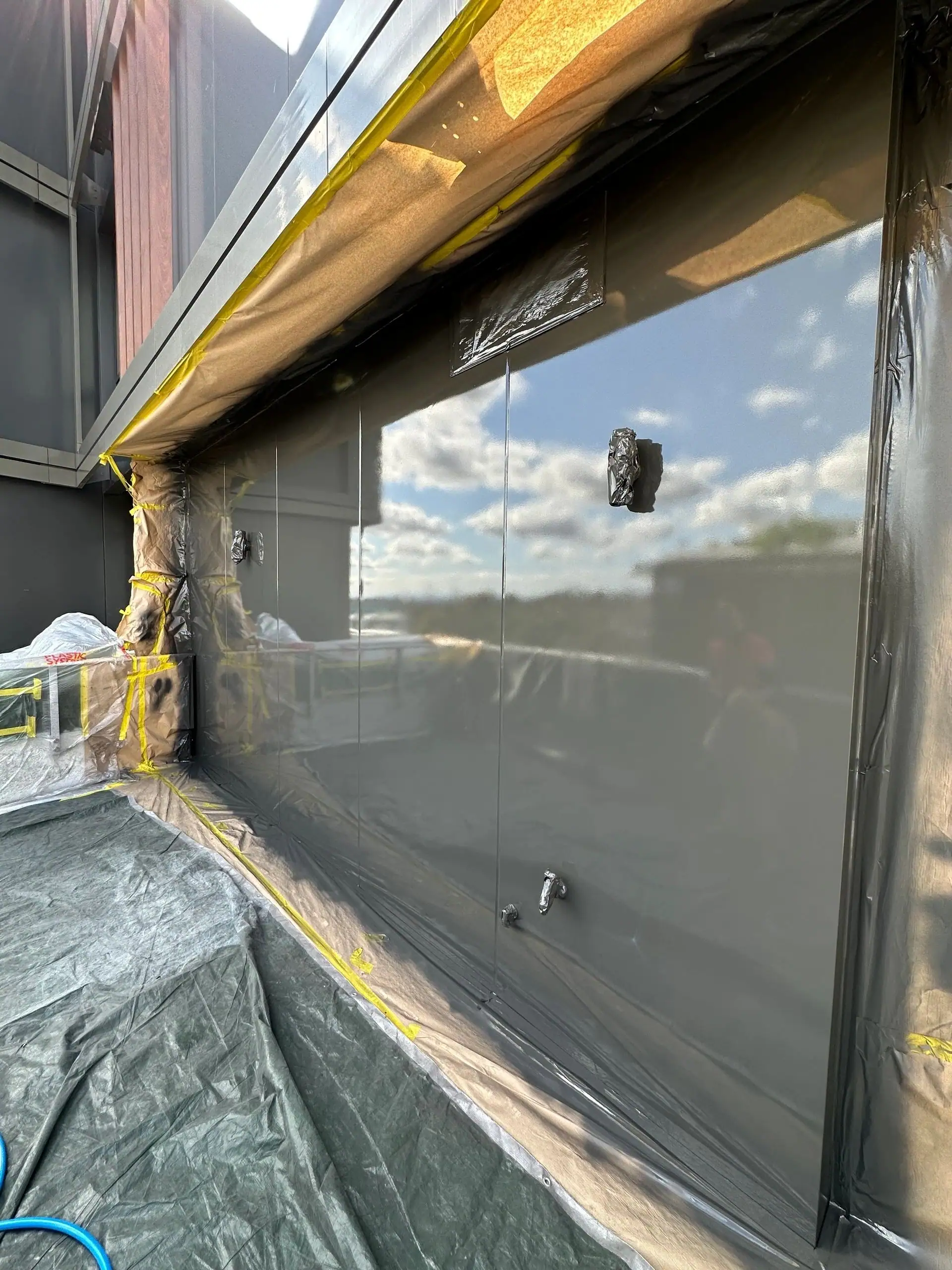 Facade glazing and framing masked with protective sheeting on an M&M jobsite