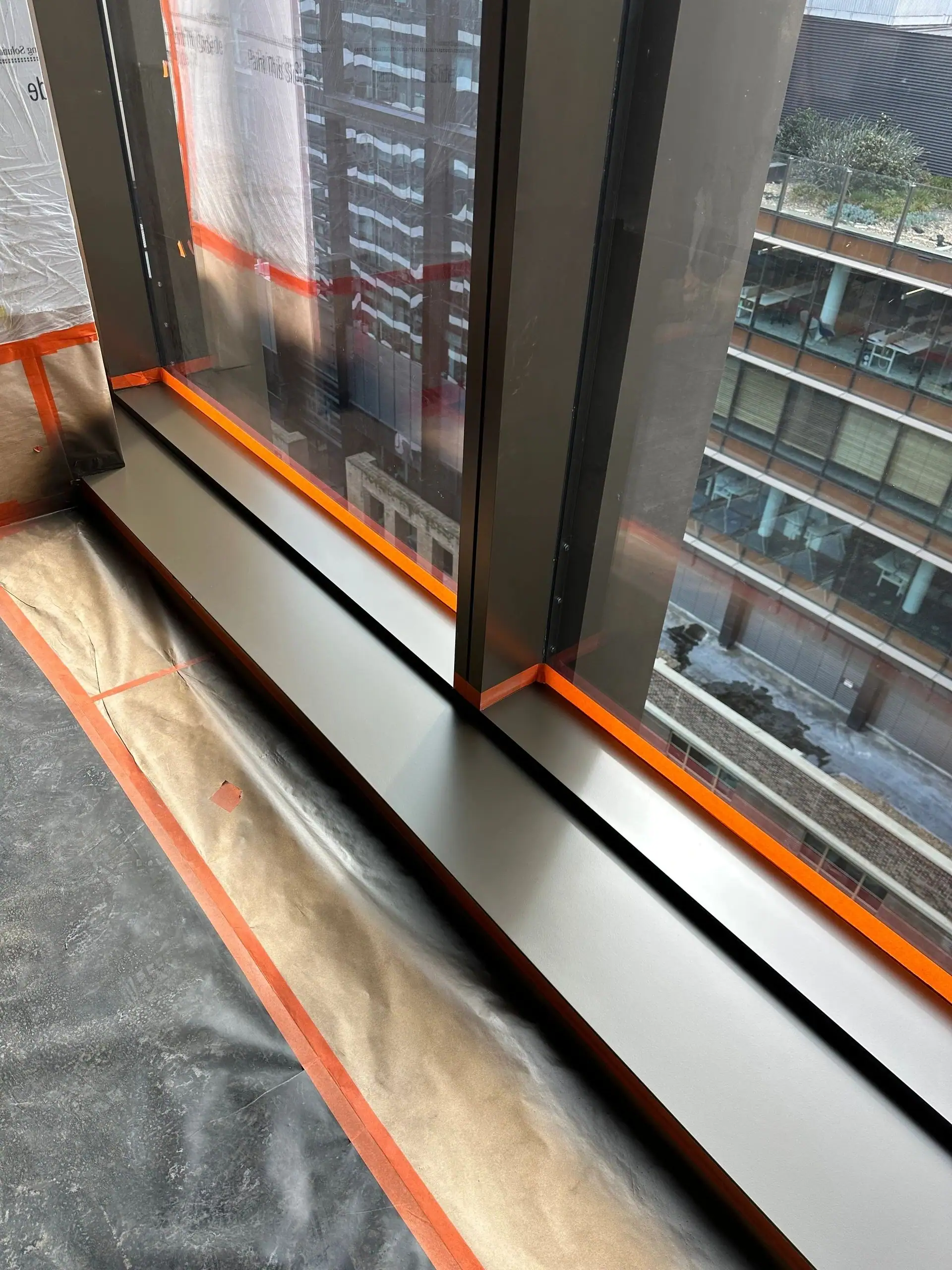 Curtain-wall detail masked and protected on an M&M jobsite